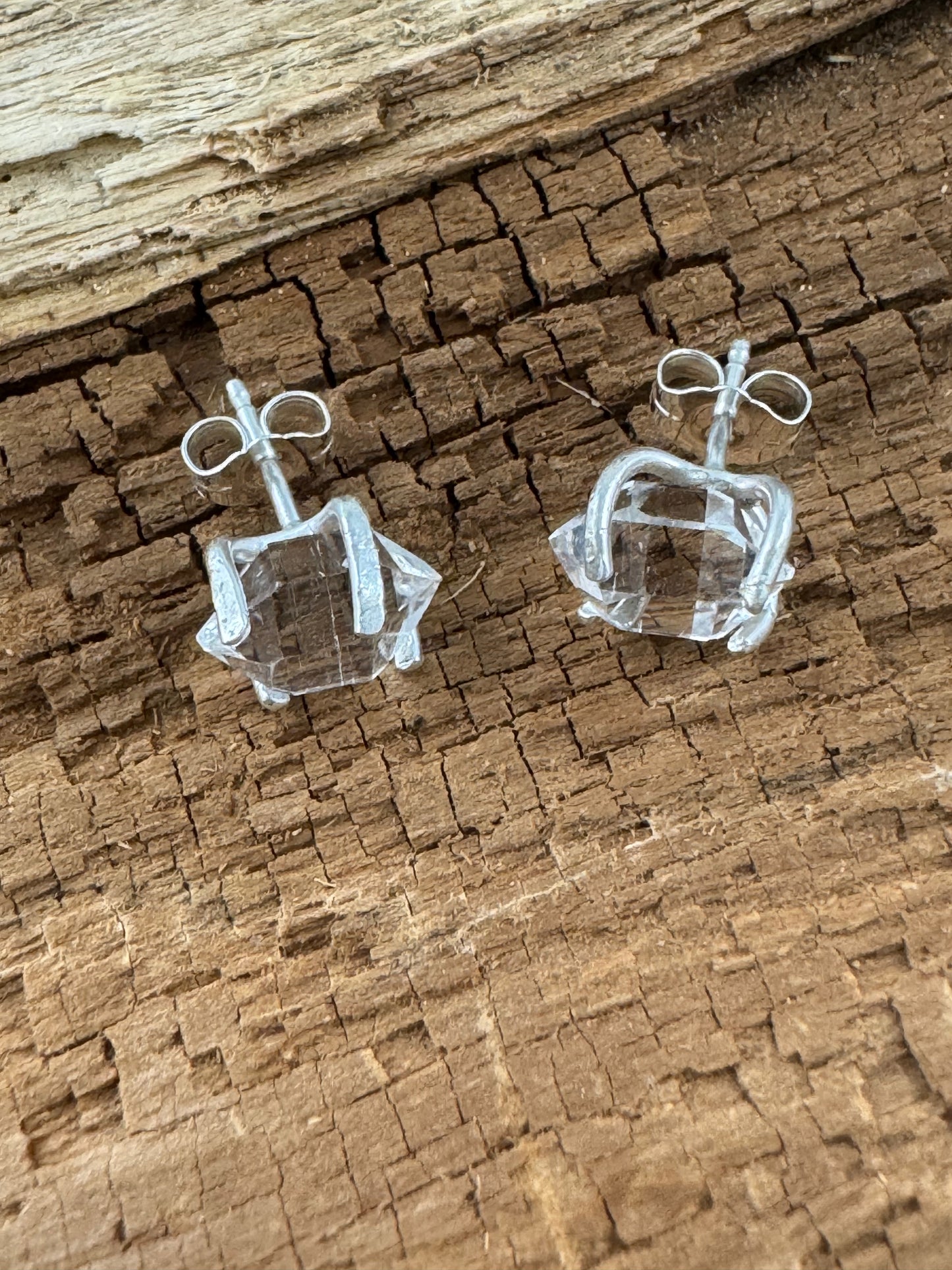 Clear crystal herkimer diamond earrings on a textured brown surface