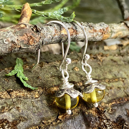 Sterling silver dangle earrings with baltic amber resting on a tree branch