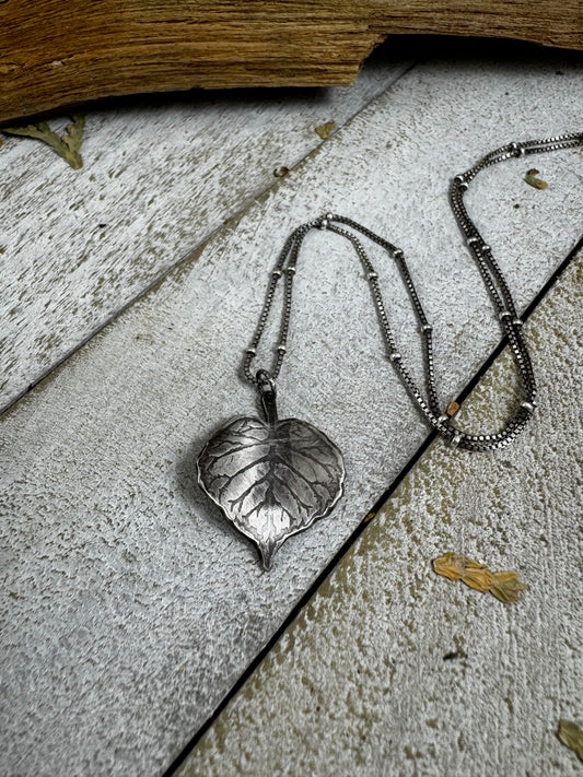 Silver leaf necklace on a weathered wood surface