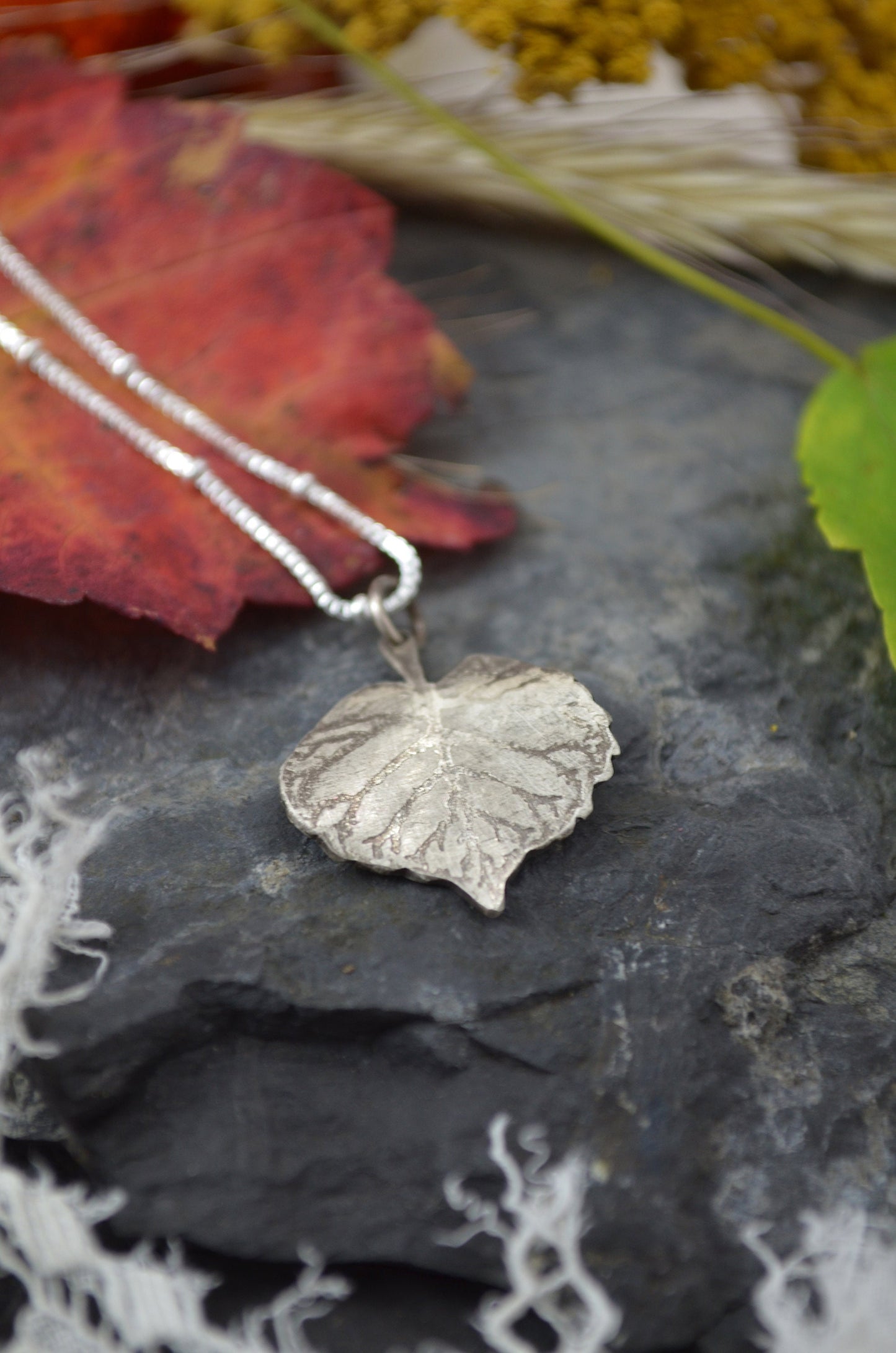 Silver Leaf necklace on stone surface with leaf accents