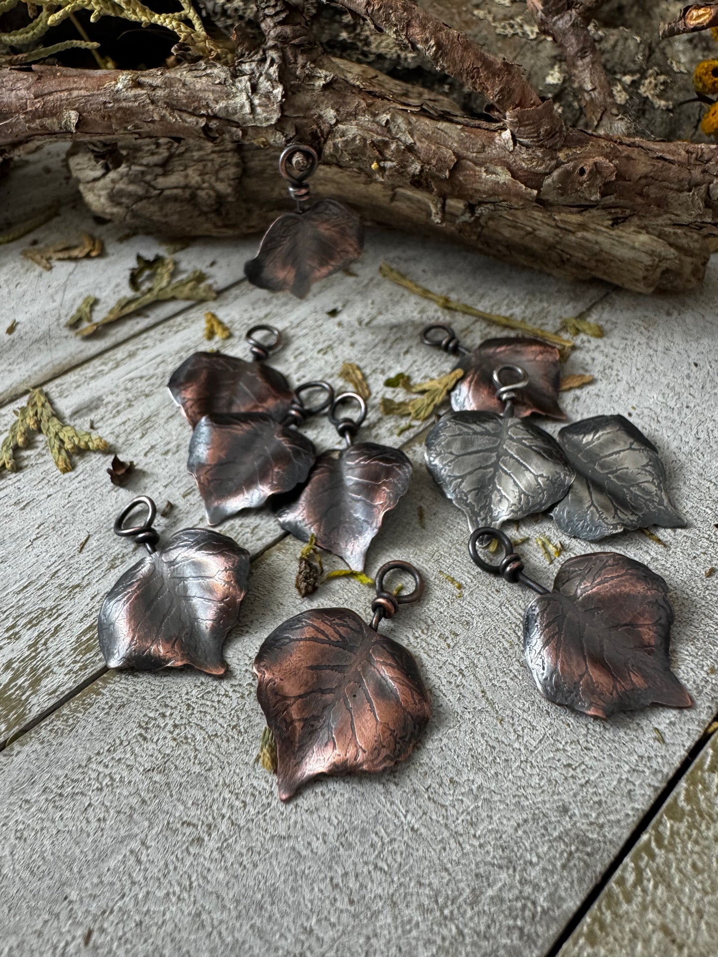 Collection of copper leaf-shaped pendants on a wooden surface