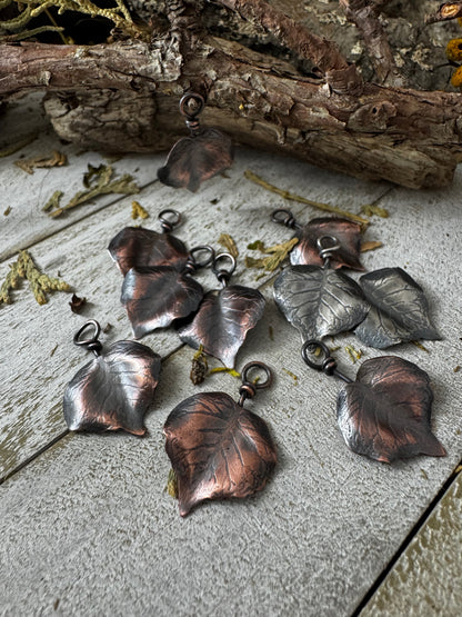 Collection of copper leaf-shaped pendants on a wooden surface