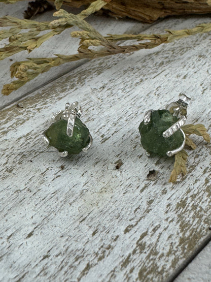 Green stone earrings with silver settings on a wooden surface