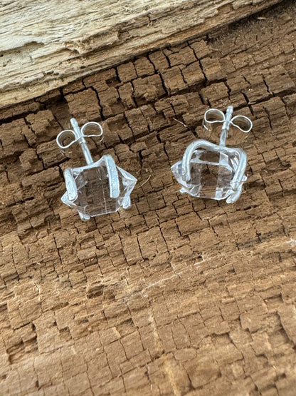 Clear crystal herkimer diamond earrings on a textured brown surface