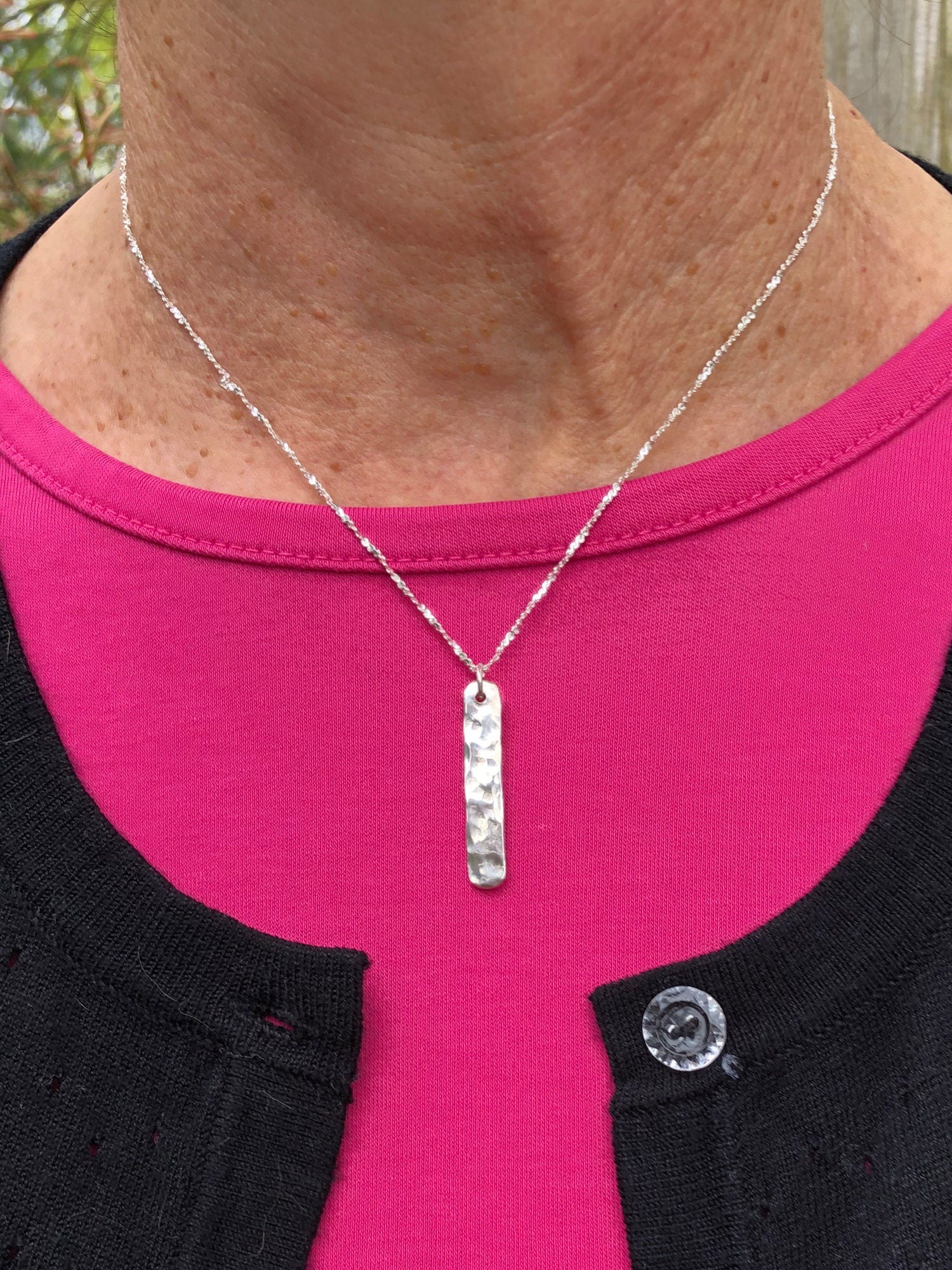 Minimalist Hammered Bar Necklace worn by a woman in a pink shirt with a black sweater