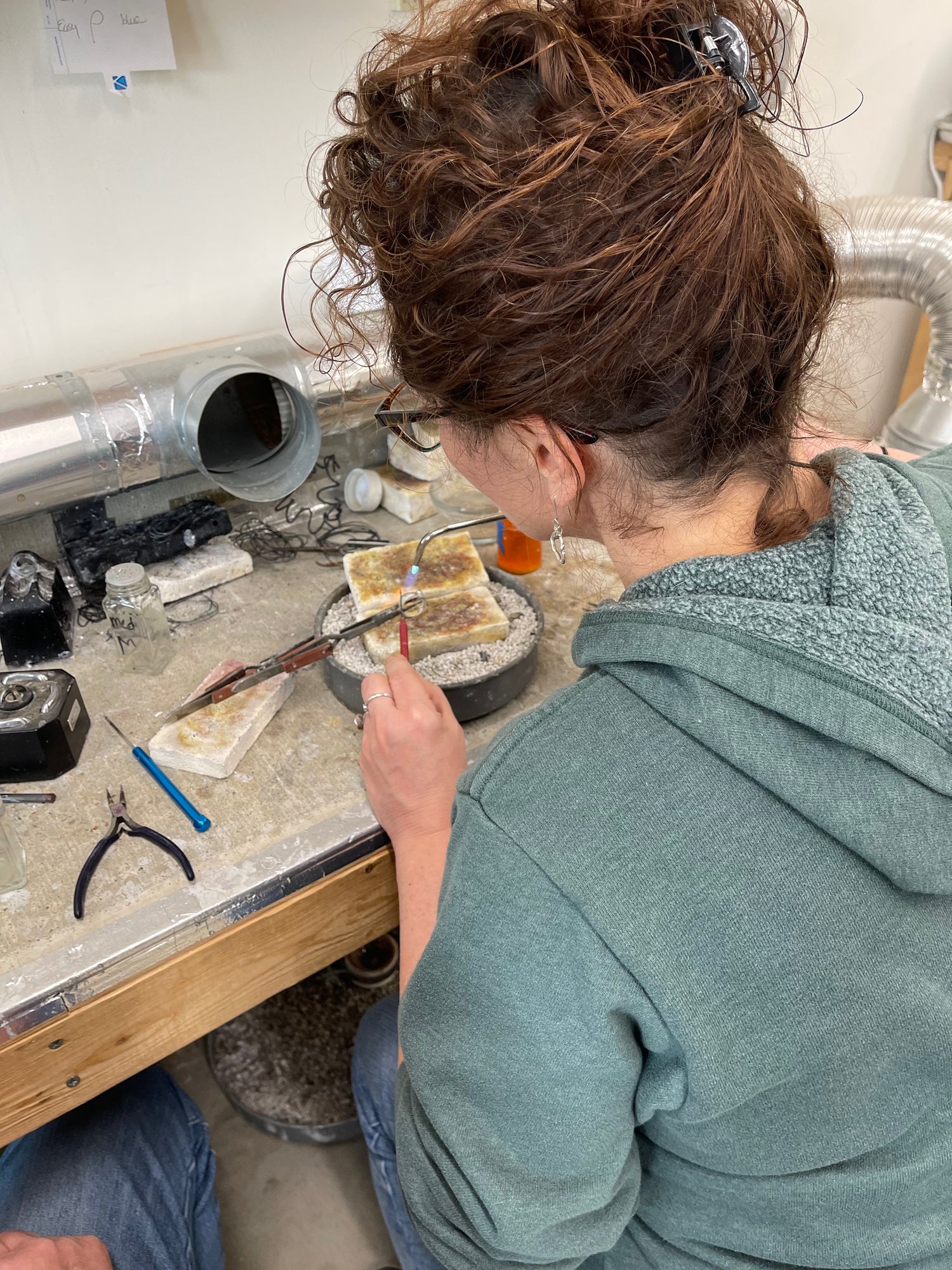 Jennifer Standley soldering a sterling silver ring on a workbench.