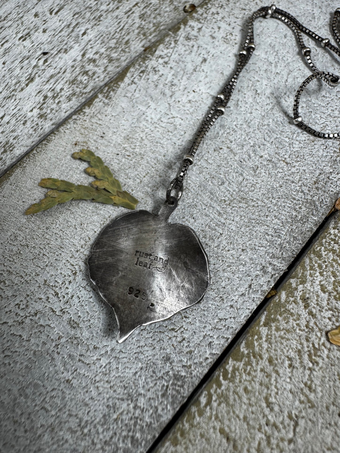 Silver pendant on a chain lying on a textured surface