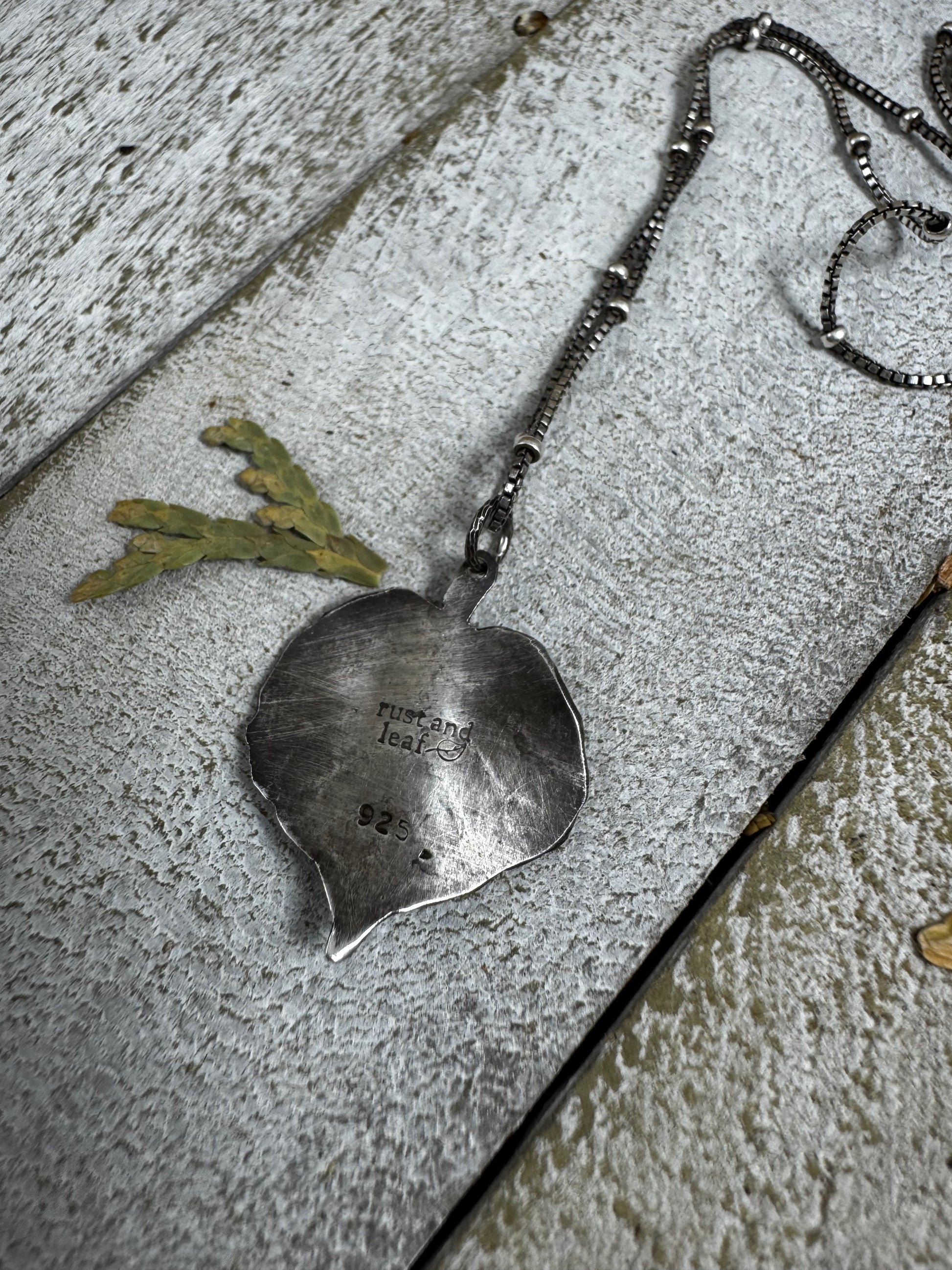 Silver pendant on a chain lying on a textured surface
