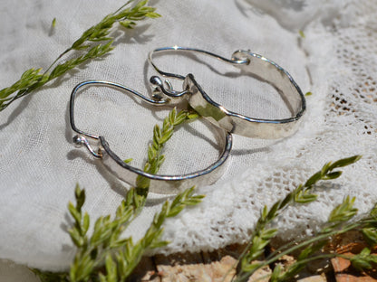 Sterling Silver Minimalist Hammered Hoops in the sunshine lying on linen and dried flowers
