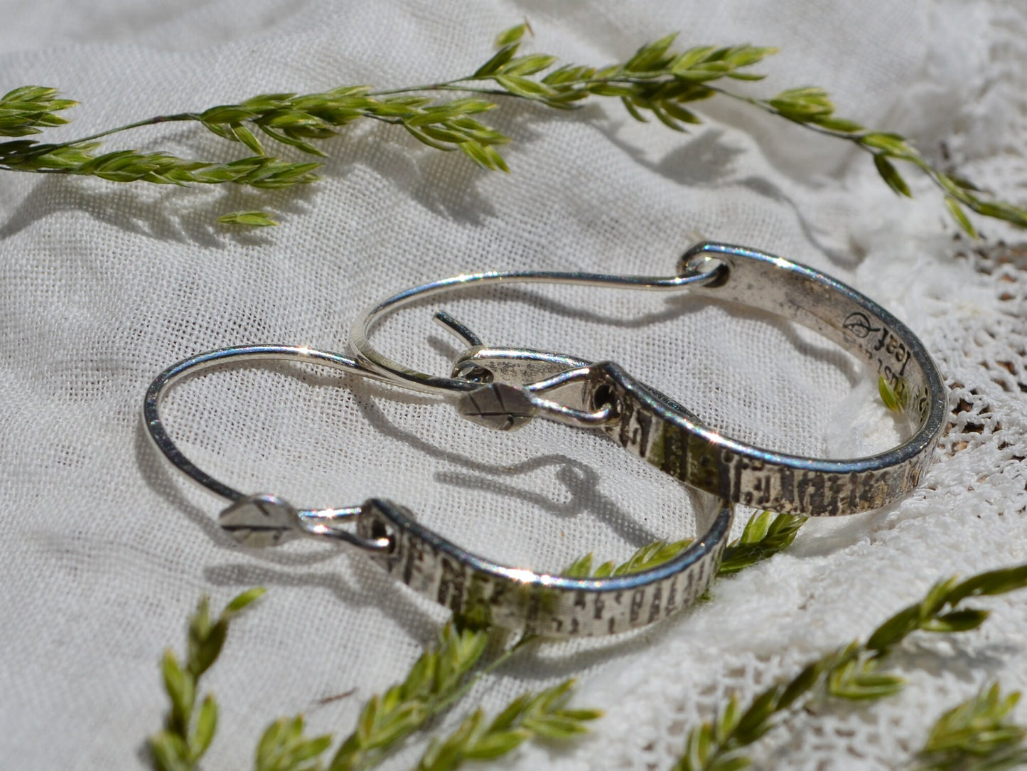 Sterling silver Tree Bark Hoops in sunshine laying on linen and dried flowers