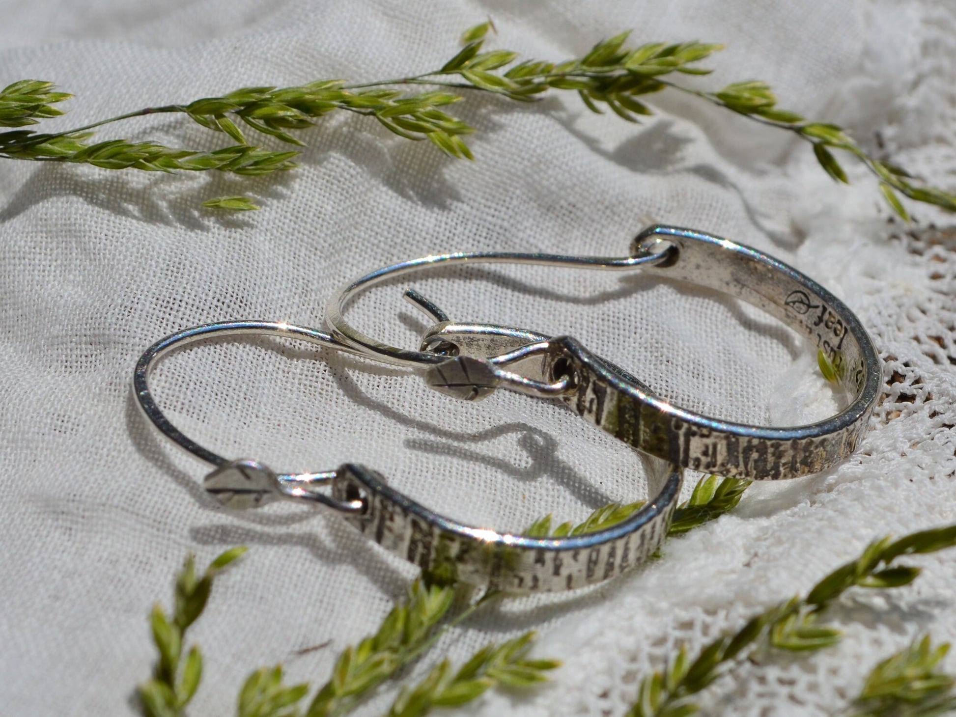 Sterling silver Tree Bark Hoops in sunshine laying on linen and dried flowers