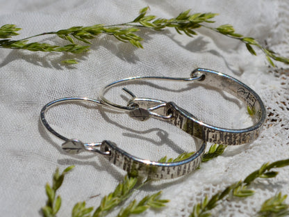 Sterling silver Tree Bark Hoops in sunshine laying on linen and dried flowers