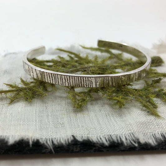 Handcrafted sterling silver cuff bracelet with organic tree bark texture, inspired by forest bark patterns and artisan metalwork.